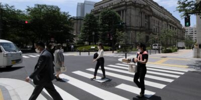 Pedestrians cross the street in front of the Bank of Japan HQ in Tokyo. The BOJ is considering issuing their own CBDC to keep up with digitalization across the region. (Photo by Kazuhiro NOGI / AFP)